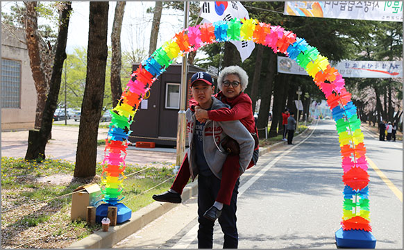 제1회 입영문화제에서 현역병 입영대상자가 어머니를 업고 사진을 촬영하고 있다. (4월 11일, 육군훈련소)