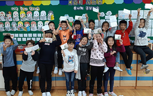 초등학교 교실 뒷편에서 아이들이 단체로 편지 들고있는 모습