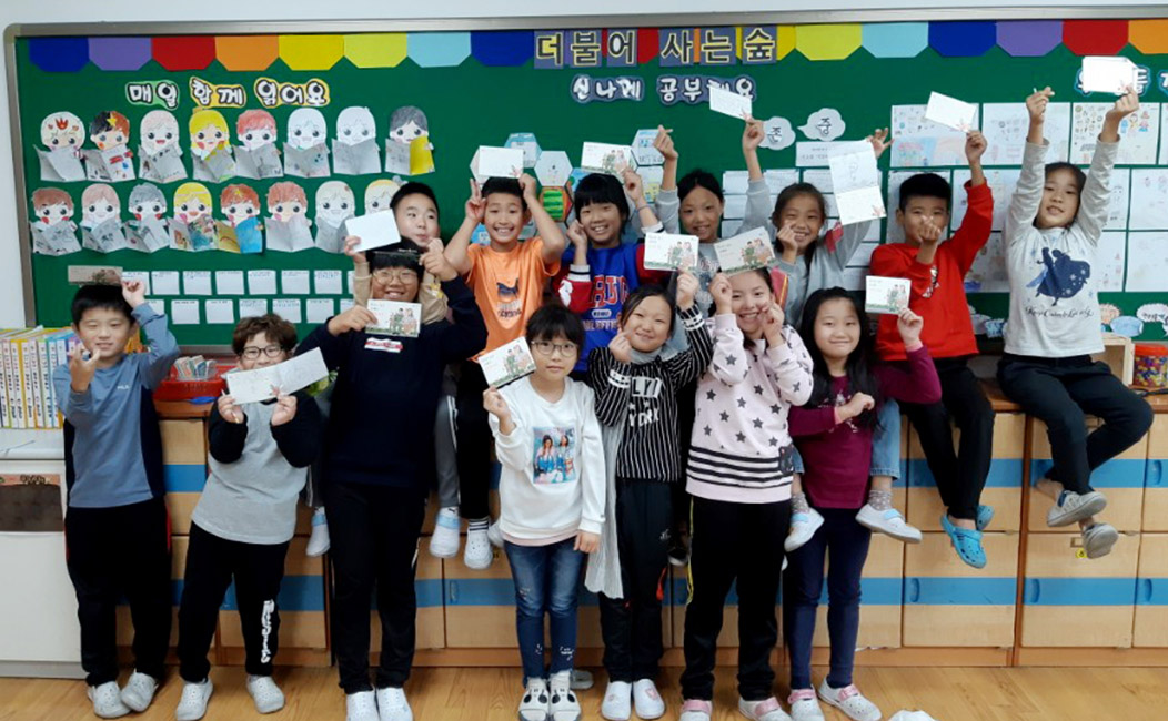 초등학교 교실 뒷편에서 아이들이 단체로 편지 들고있는 모습