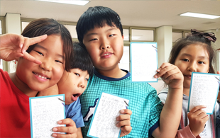 남자, 여자 초등학생들이 익살스러운 표정으로 감사편지를 들고있는 모습