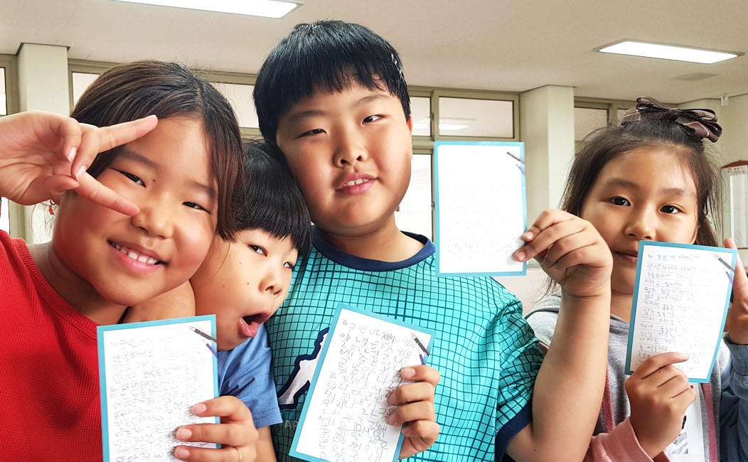 '남자, 여자 초등학생들이 익살스러운 표정으로 감사편지를 들고있는 모습