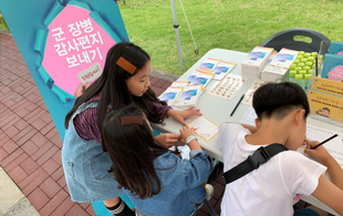 여자 아이가 나란히 앉은 남자, 여자아이의 편지 쓰는 것을 알려주는 모습