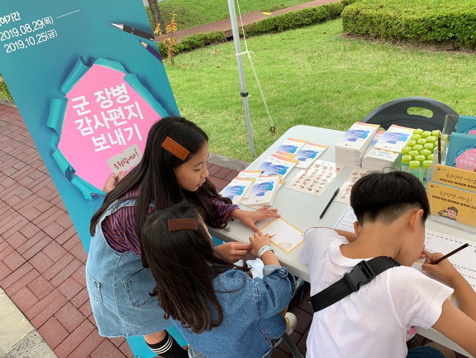여자 아이가 나란히 앉은 남자, 여자아이의 편지 쓰는 것을 알려주는 모습