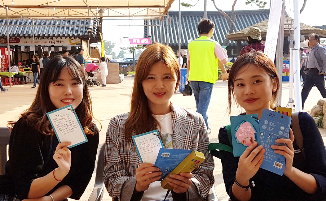 세명의 여성이 나란히 앉아 편지를 들고웃고 있는 모습